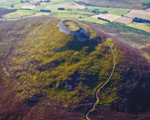 Aerial photograph of Tap o’ Noth, showing the vitrified oblong fort at the summit and the remnants of the outer fort below
