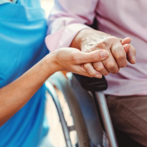 Nurse consoling a senior woman in the nursing home holding her hand