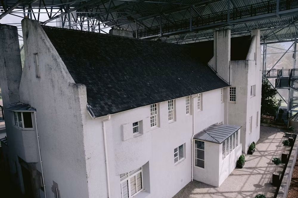 Caption: The Hill House in Helensburgh, designed by Charles Rennie Mackintosh, stands beneath the protective Hill House Box, which has sheltered the building from rain while its